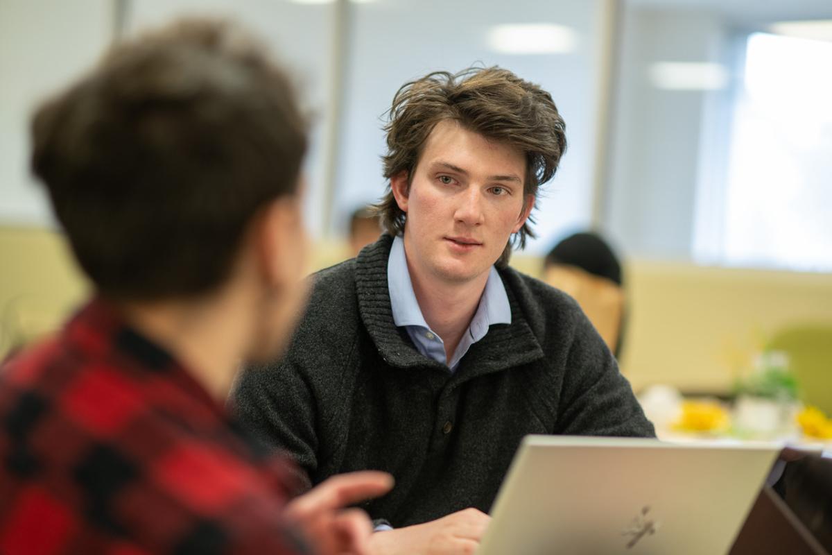 Student in front of laptop wearing grey shirt.
