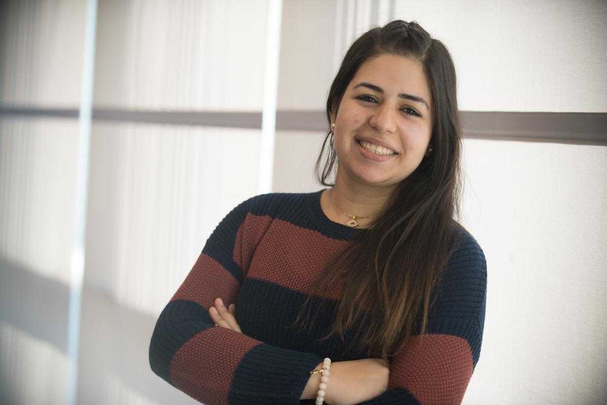 Management student smiling wearing a striped sweater.