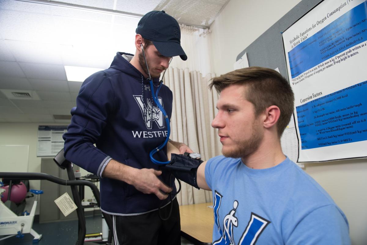 Movement Science student practicing blood pressure measurement on a classmate during a hands-on lab activity.