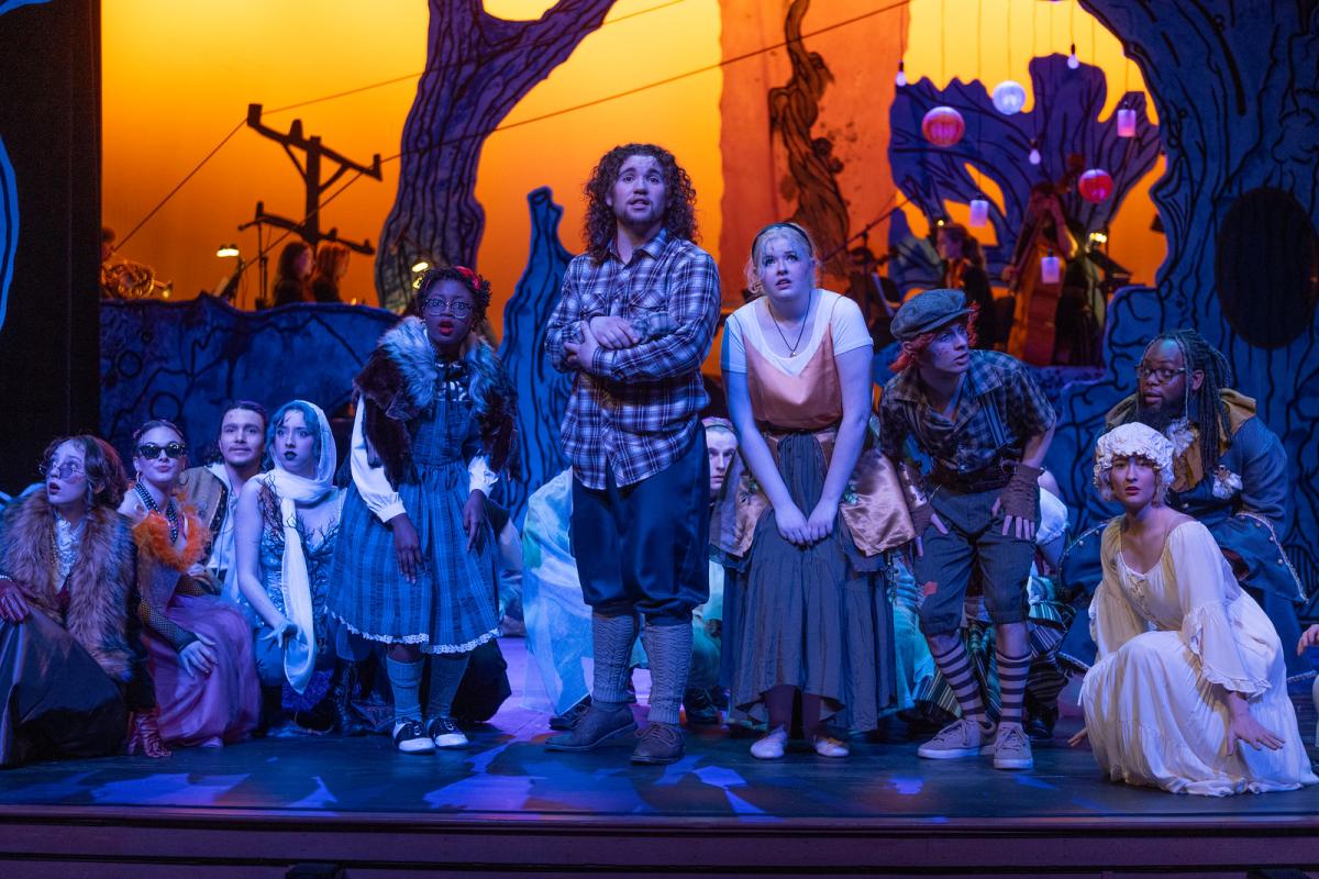 Group of students in costume performing in a scene from the production Into the Woods.