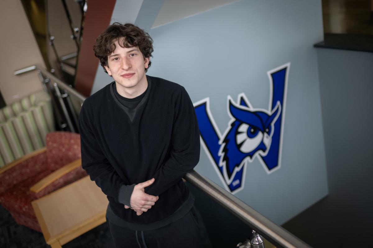Health sciences student smiling with Westfield State owl logo behind him.