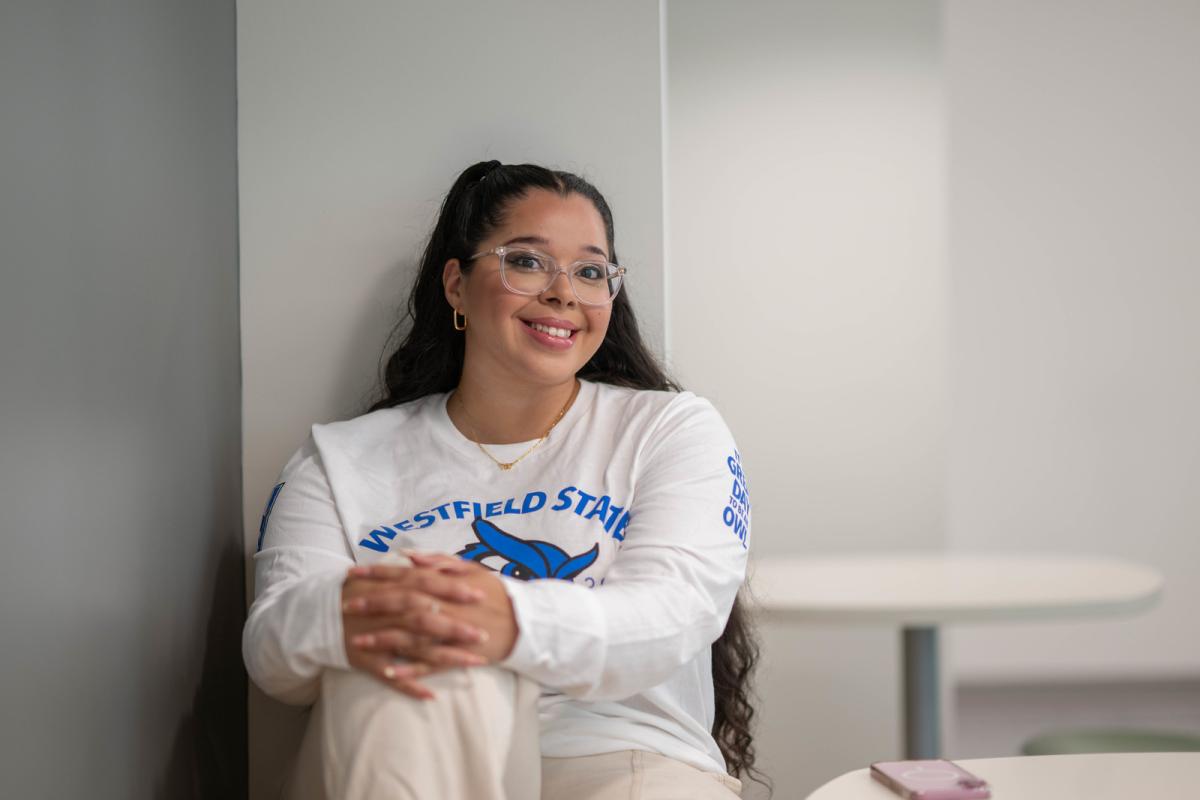 Smiling psychology student wearing a Westfield State University shirt inside a campus building.