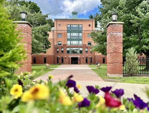 Courtney Hall in the summer with colorful flowers in front of the building