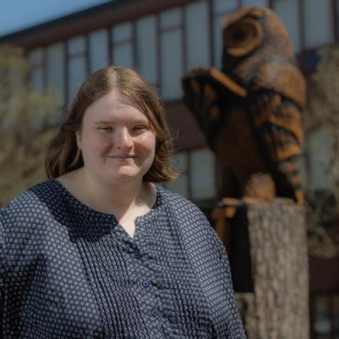 Melissa Costello smiling on campus in front of an owl statue.