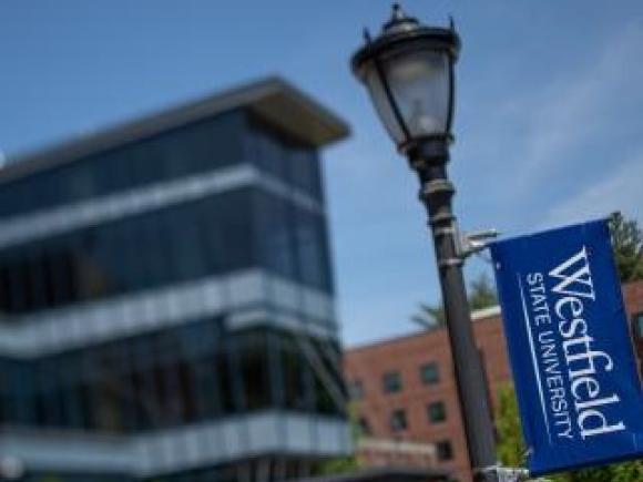 Foreground light pole with Westfield State University banner and Ely building in background.