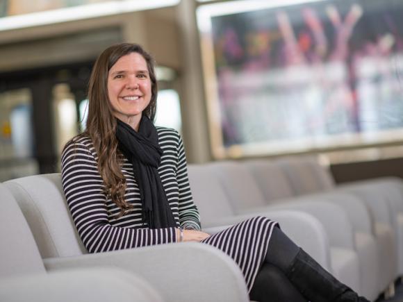 Bethany Mather, a teacher at Farmington River Regional School and alumna of Westfield State University, was recently named this year’s Massachusetts University Educator Alumni Award recipient. She's sitting in the lobby at Horace Mann, in a gray chair. An unfocused window is behind her.