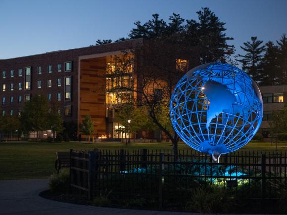 Campus globe at night with University Hall in the background.