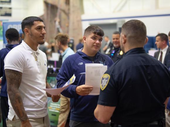 Two criminal justice students talking with an officer. 