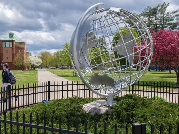 Globe in the spring with flowering trees behind it.
