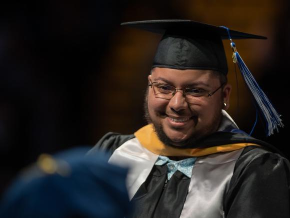 Student smiling at graduate commencement.