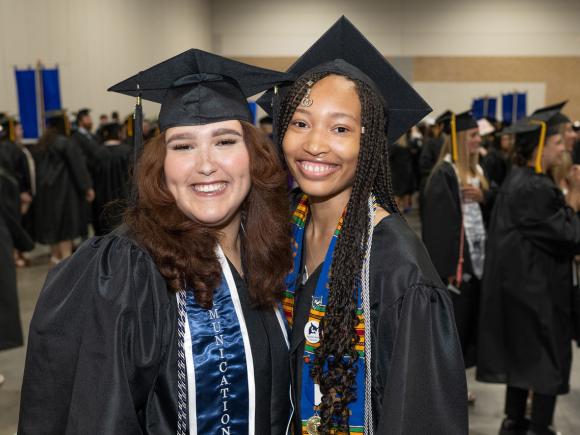 Two students smiling at undergraduate commencement.