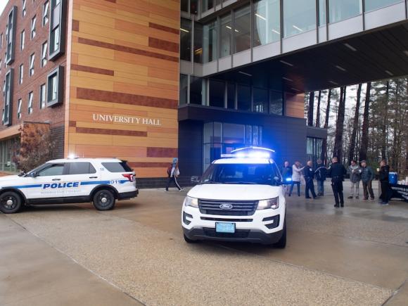 Two police vehicles are parked in front of University Hall, with a small crowd of people loading supplies for the Stuff-a-Cruiser event.