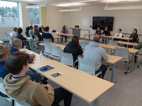 English workshop featuring students and faculty sitting at tables chatting.