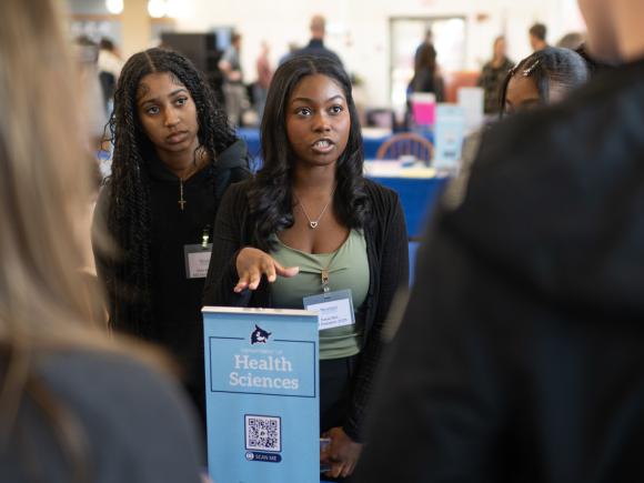 Health sciences student engaging with prospective students at an admissions open house.