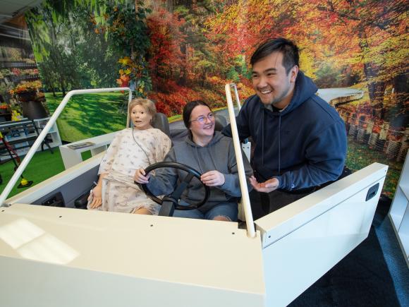 Two Occupational Therapy students practice with a simulated patient in a car during a lab session.