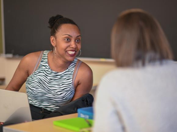 Two students smiling as they engage in a classroom discussion.