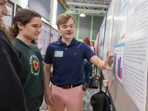 History students discussing an undergraduate research poster presentation.