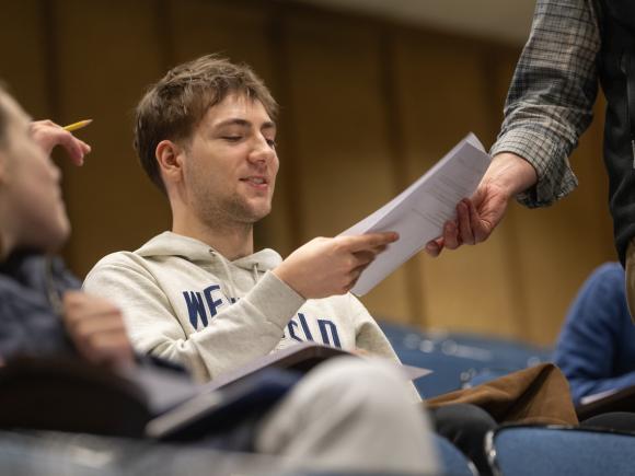 Student in a classroom seminar receiving a paper to review.