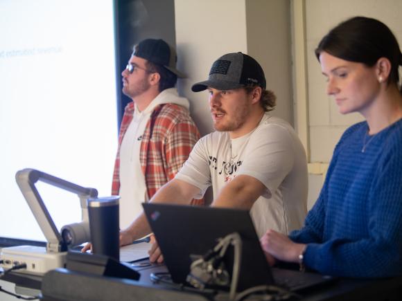 Three management students giving a classroom presentation.
