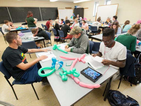 Students in a math class creating balloon animals as part of a hands-on project.