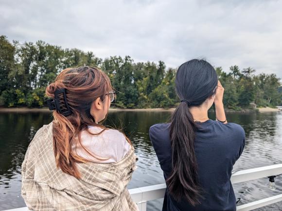 Two students looking out over a scenic river.