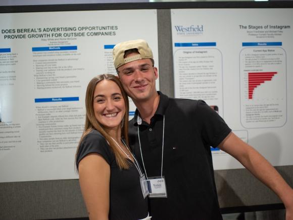 Two students smiling while presenting their undergraduate research project.