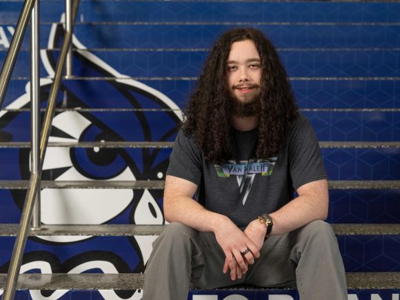 Nathan Hutnak smiling on stairs with Nestor owl logo.