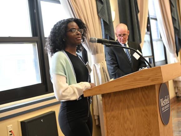 Student delivering a speech at a podium in front of an audience.