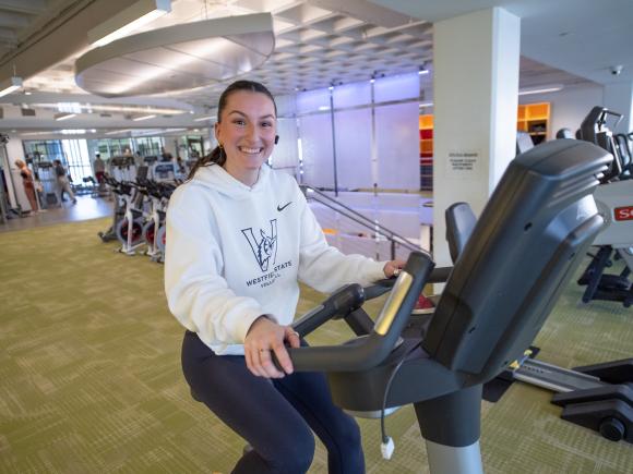 Student riding a stationary bike during a workout in the campus fitness center.