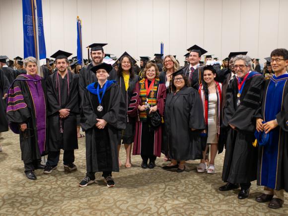 Political science faculty and students smiling together at commencement ceremony.