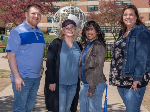 SAIL staff group photo with four staff members smiling in front of the campus globe.