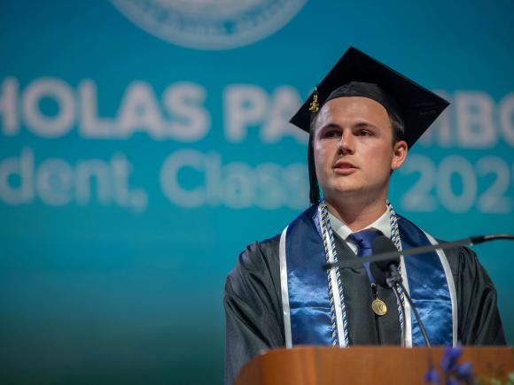 Man stands at podium in academic regalia