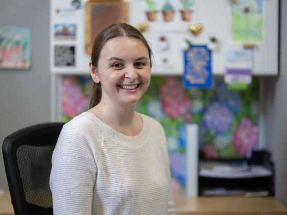 Student smiling at an internship sitting at a desk.