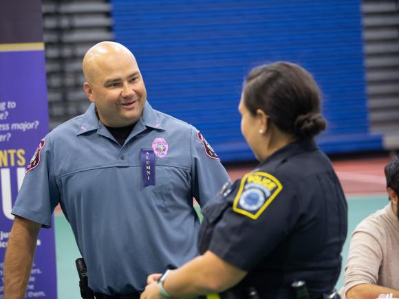 Criminal justice alumni speaking with a police officer at the Criminal Justice Career Fair.