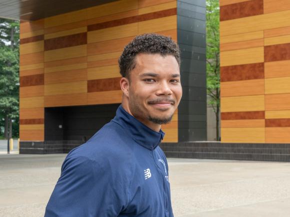 Smiling student standing in front of University Hall on campus.