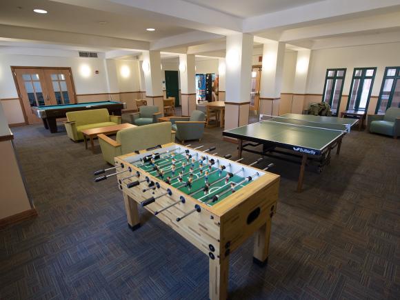 Lounge area inside Courtney Hall featuring couches and a foosball table.
