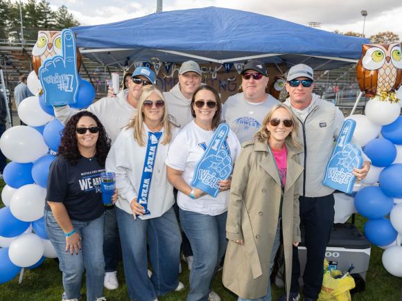 Alumni stand in front of decorated Homecoming tent