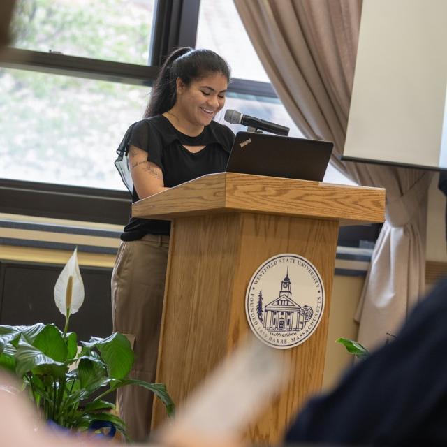 SGA student smiling at banquet ceremony in front of a podium.
