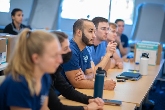 Students attentively listening to an instructor during a splinting lab session.