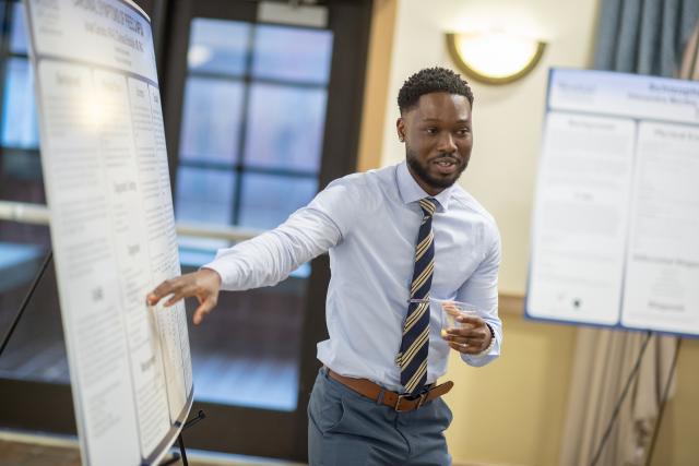 A Health Sciences student presents a research poster to an audience.