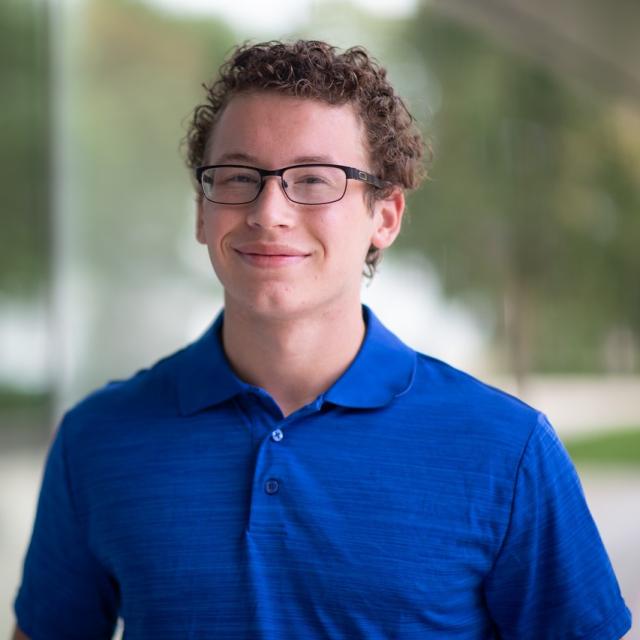 Political Science student smiling with natural light streaming through a nearby window.