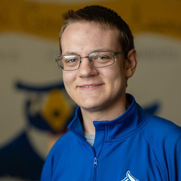 SGA Vice President of Student Life Travis wearing a blue shirt smiling.