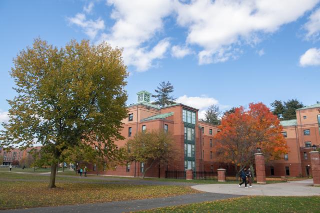 Courtney Hall in the fall with colorful foliage and two students walking in front.