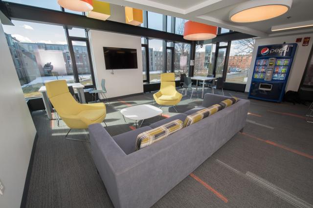 Interior of Davis Hall lounge with modern furniture and vending machine.