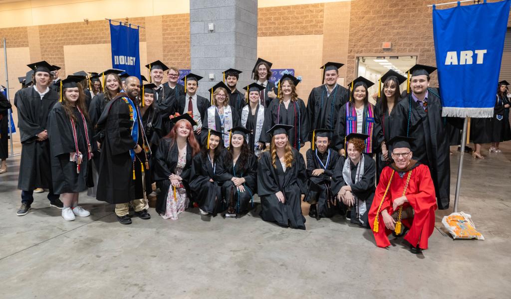 Art students smiling with faculty members at undergraduate commencement.