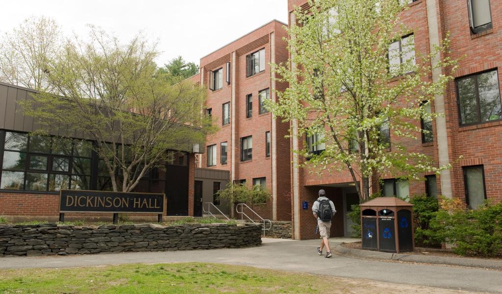 Student walking into Dickinson Hall with a flowering tree in front.