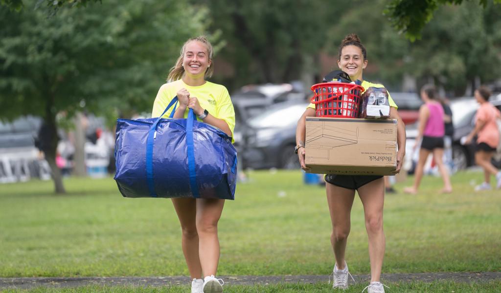 Two students carrying items to move-in to their dorm.