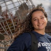 Stephanie Block, Class of 2025, a psychology major. She's posing in front of the campus globe and wearing a blue "Westfield State" shirt.