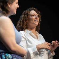 Two women stand on stage and sing