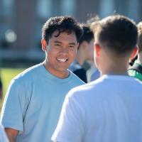 Two students chatting on the campus green on a sunny day.